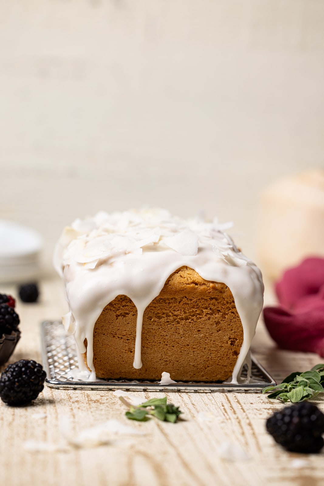 Forward shot of bread with glaze and coconut flakes and blackberries.