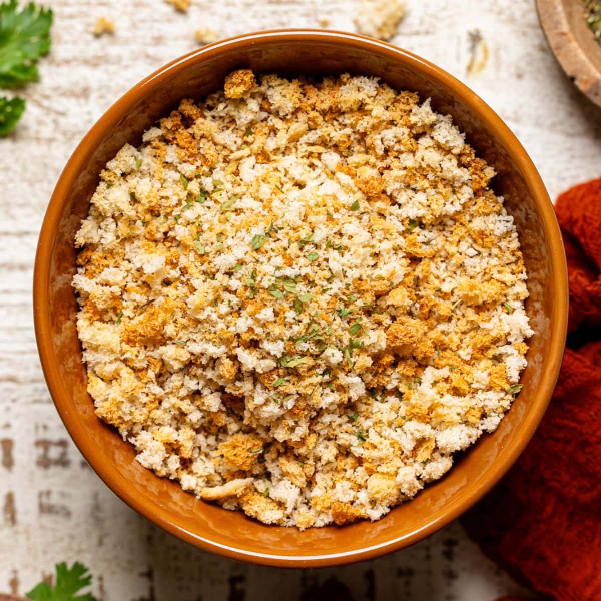 Bread crumbs in a bowl with a red napkin and seasoning.