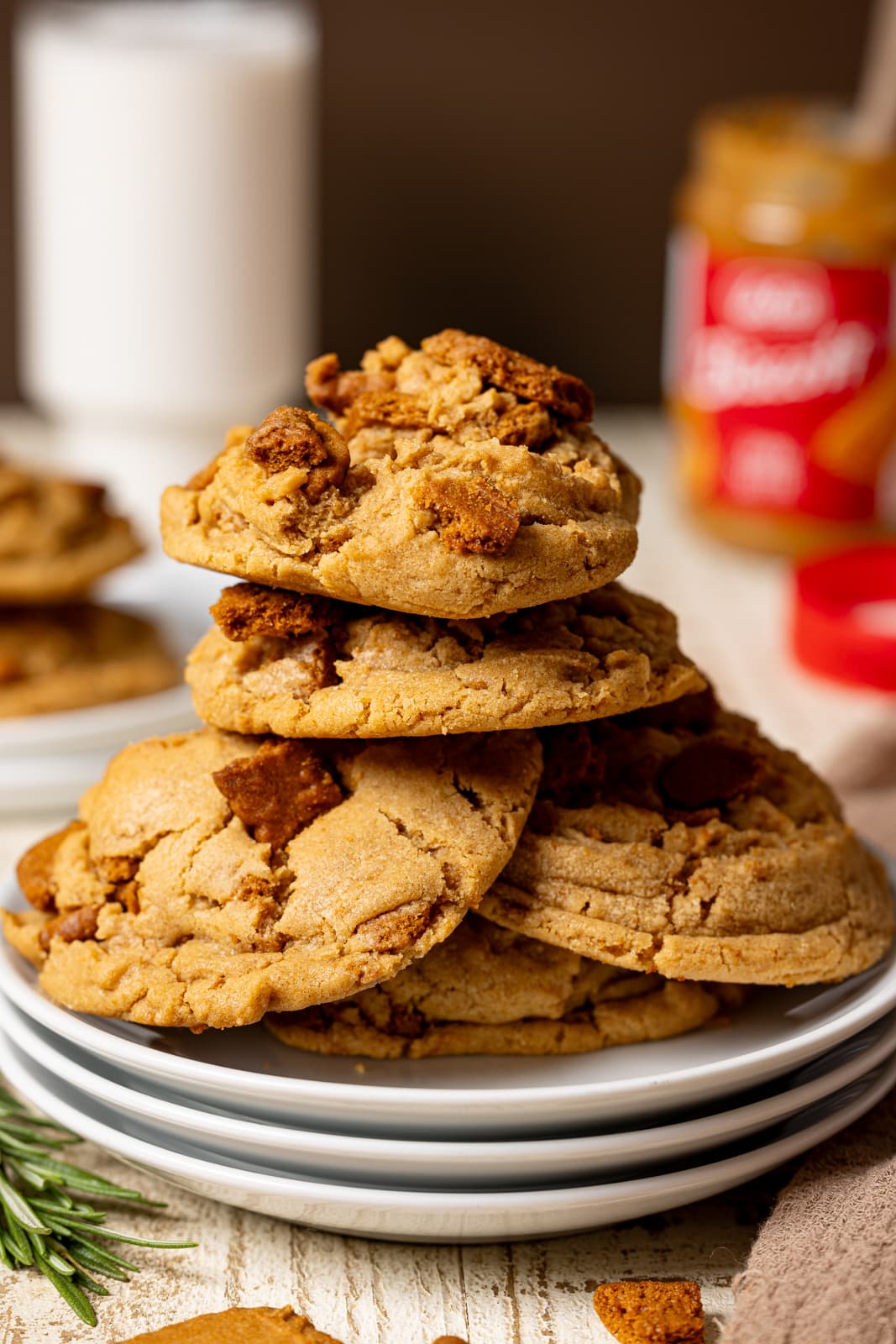 Cookies stacked with more cookies in the background, milk, and cookie butter.