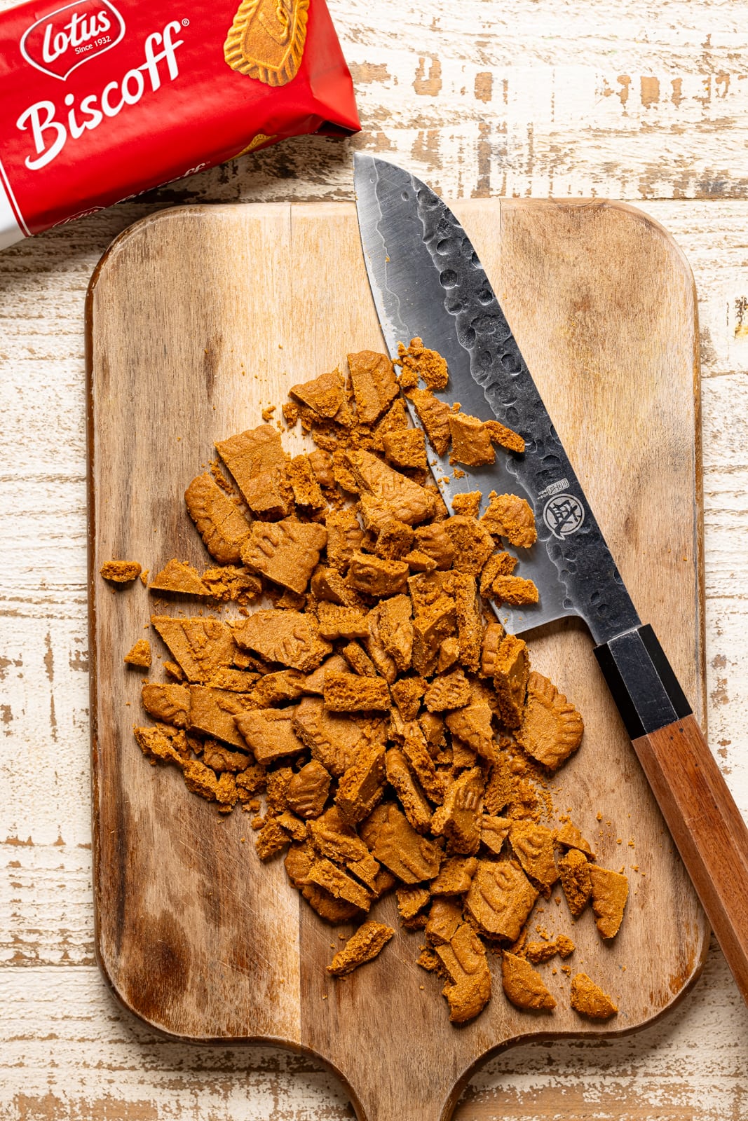 Chopped biscoff cookies on a cutting board with a knife.