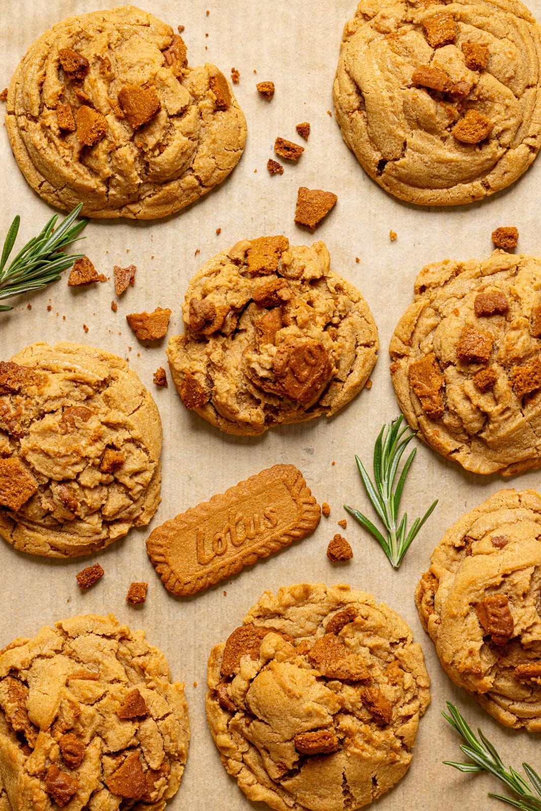 Baked cookies on a baking sheet with rosemary leaves and biscoff cookies.