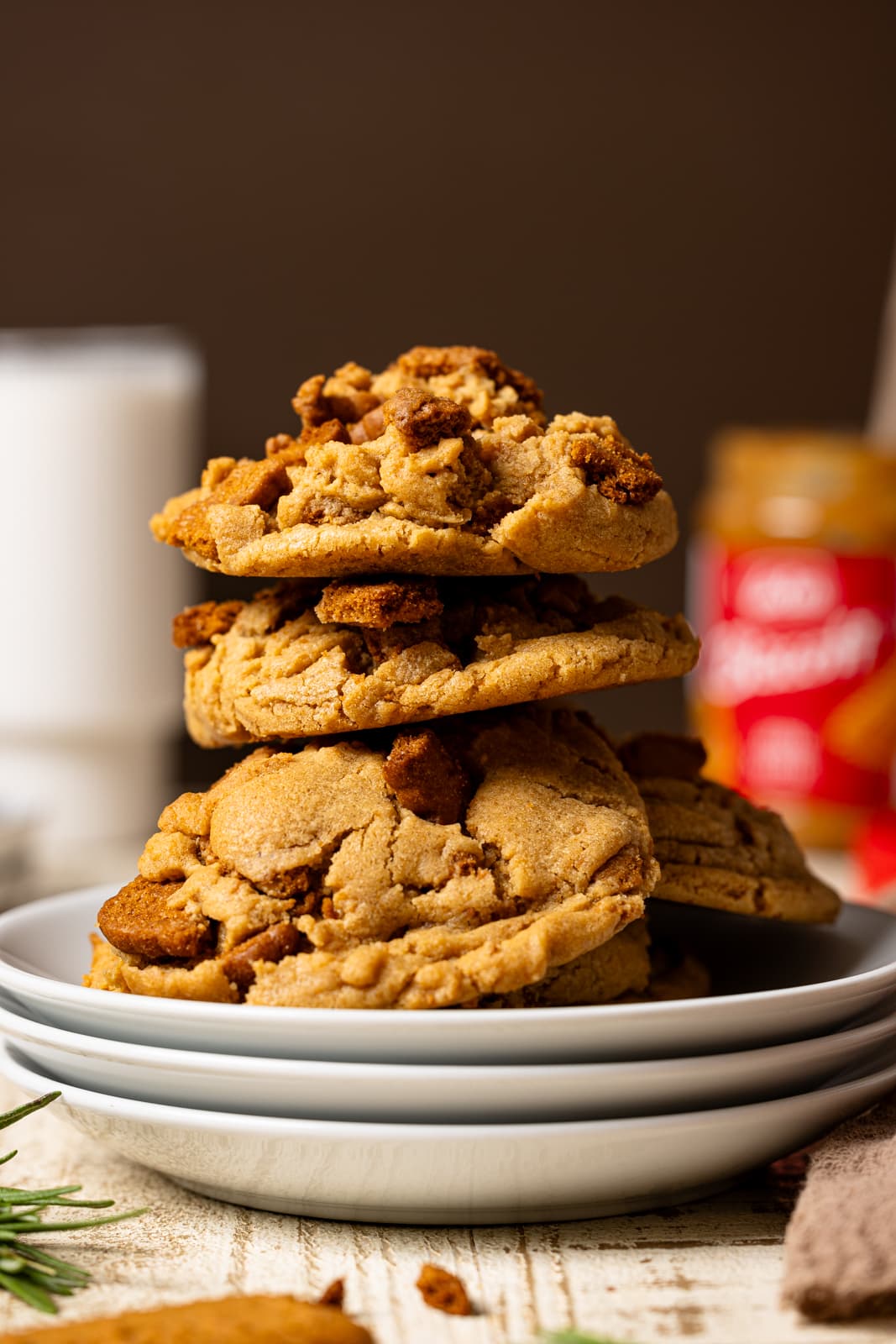 Up close shot of stacked cookies on three white plates with milk and cookie batter in background. 