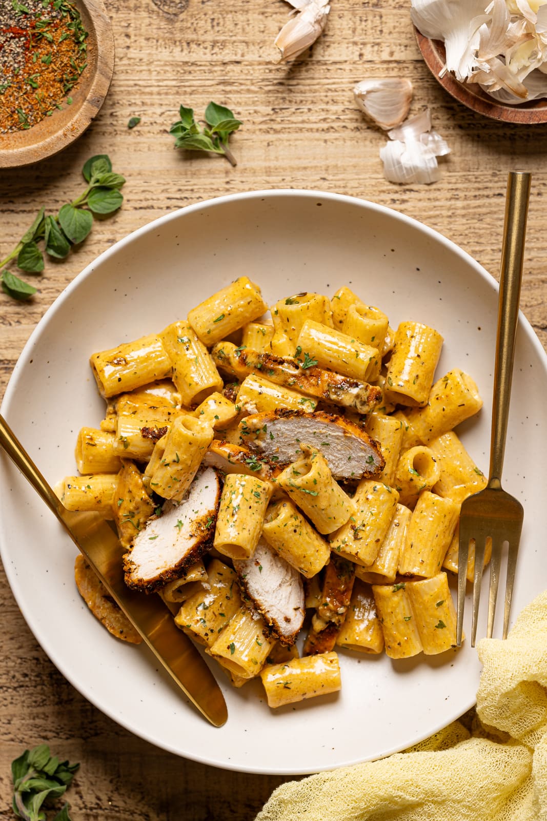 Pasta in a white plate with a fork and knife.