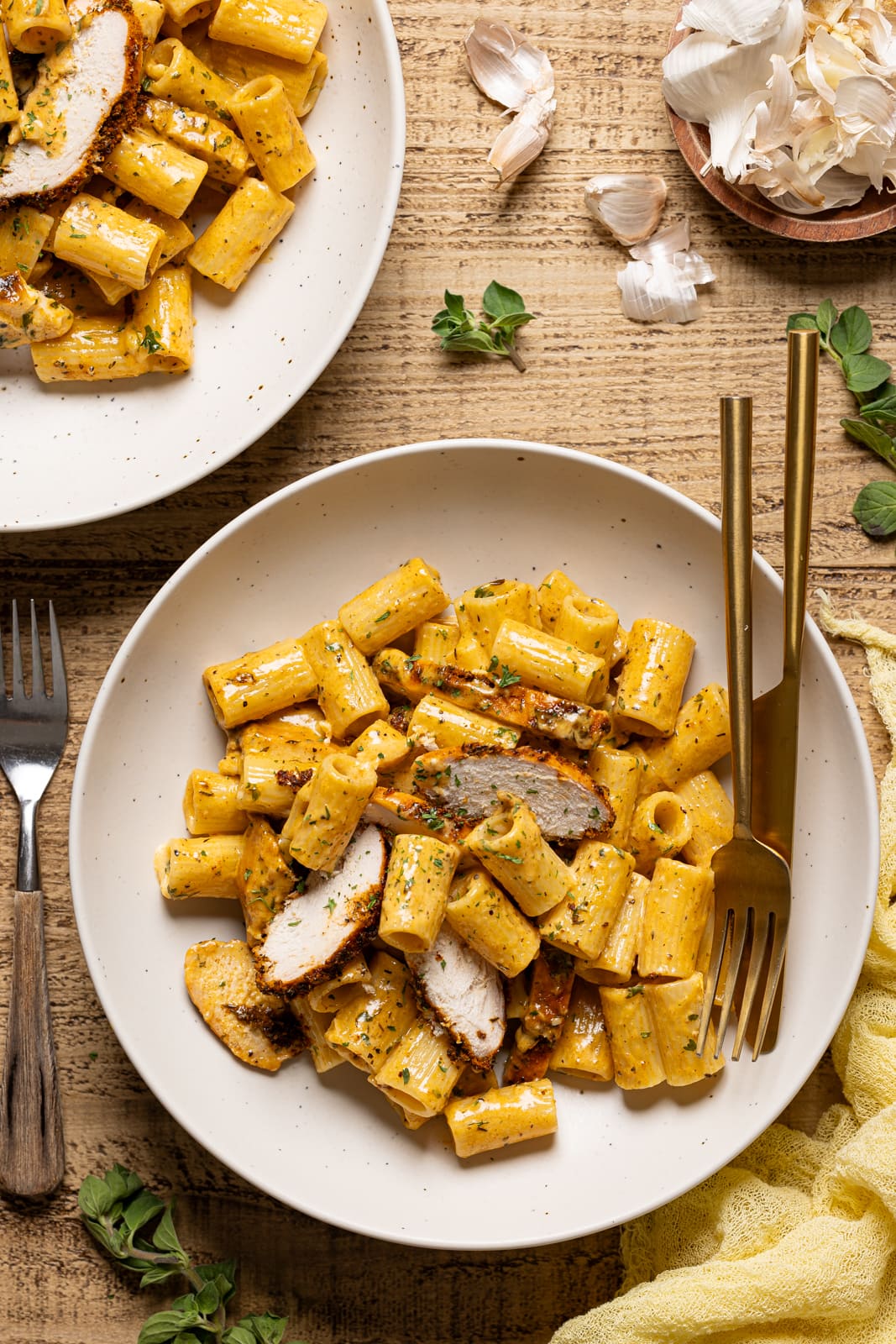 Chicken pasta in two plates with forks and a knife.