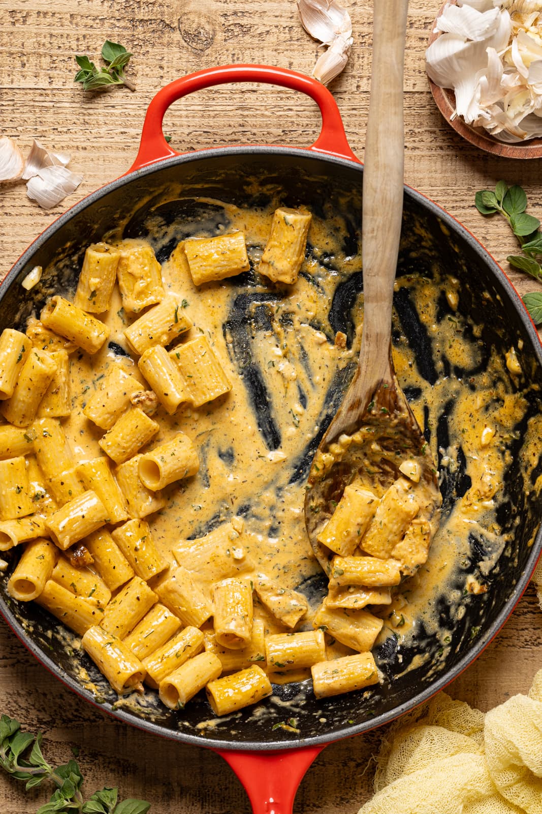 Creamy pasta in a red skillet with a wooden spoon.