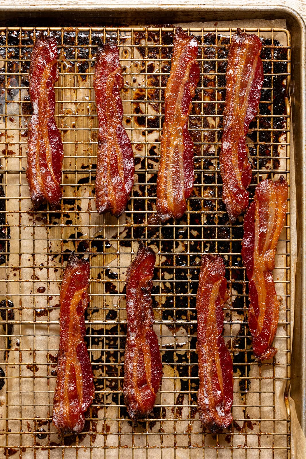Cooked bacon on a wire rack on a baking sheet for the candied bacon recipe