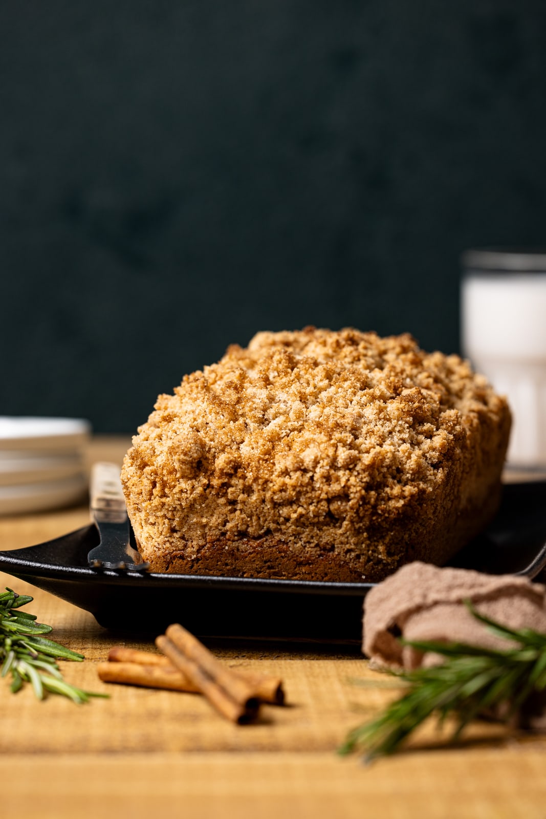 Baked bread on a black platter with a glass of milk in the background.