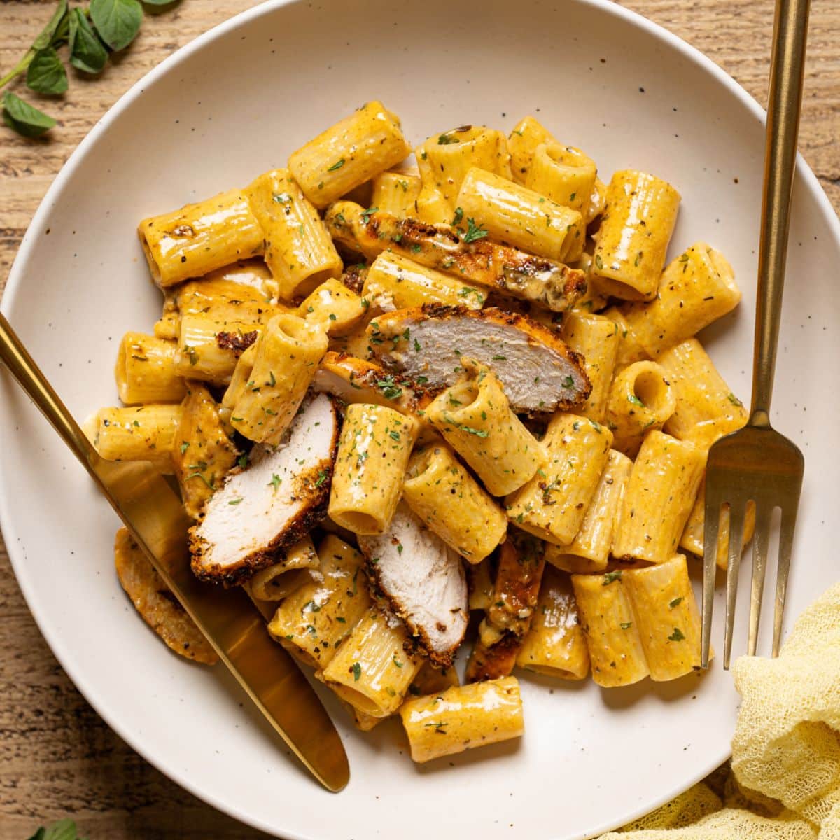 Pasta in a white plate with a fork and knife.