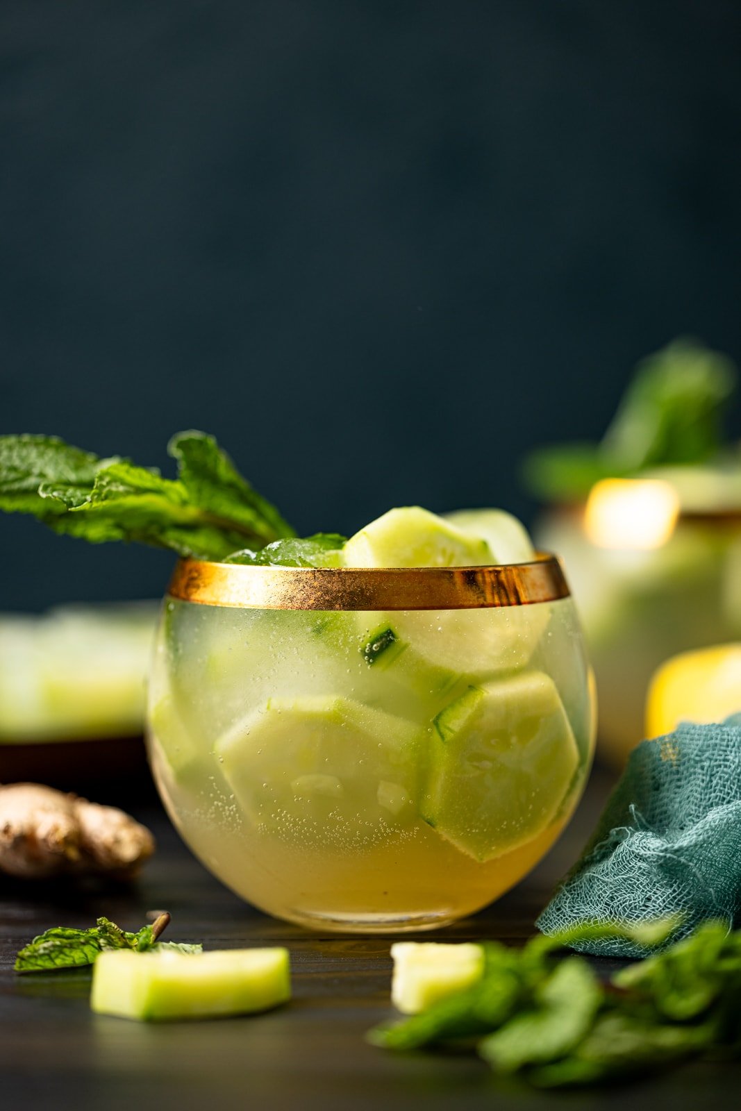 Two glasses of cucumber mint mocktail with lemon, ginger root, and fresh mint.