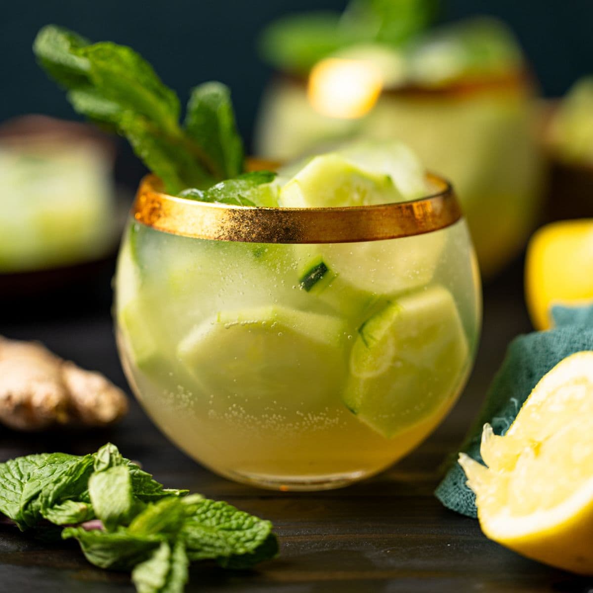 Two glasses of mocktails with lemons and herbs.
