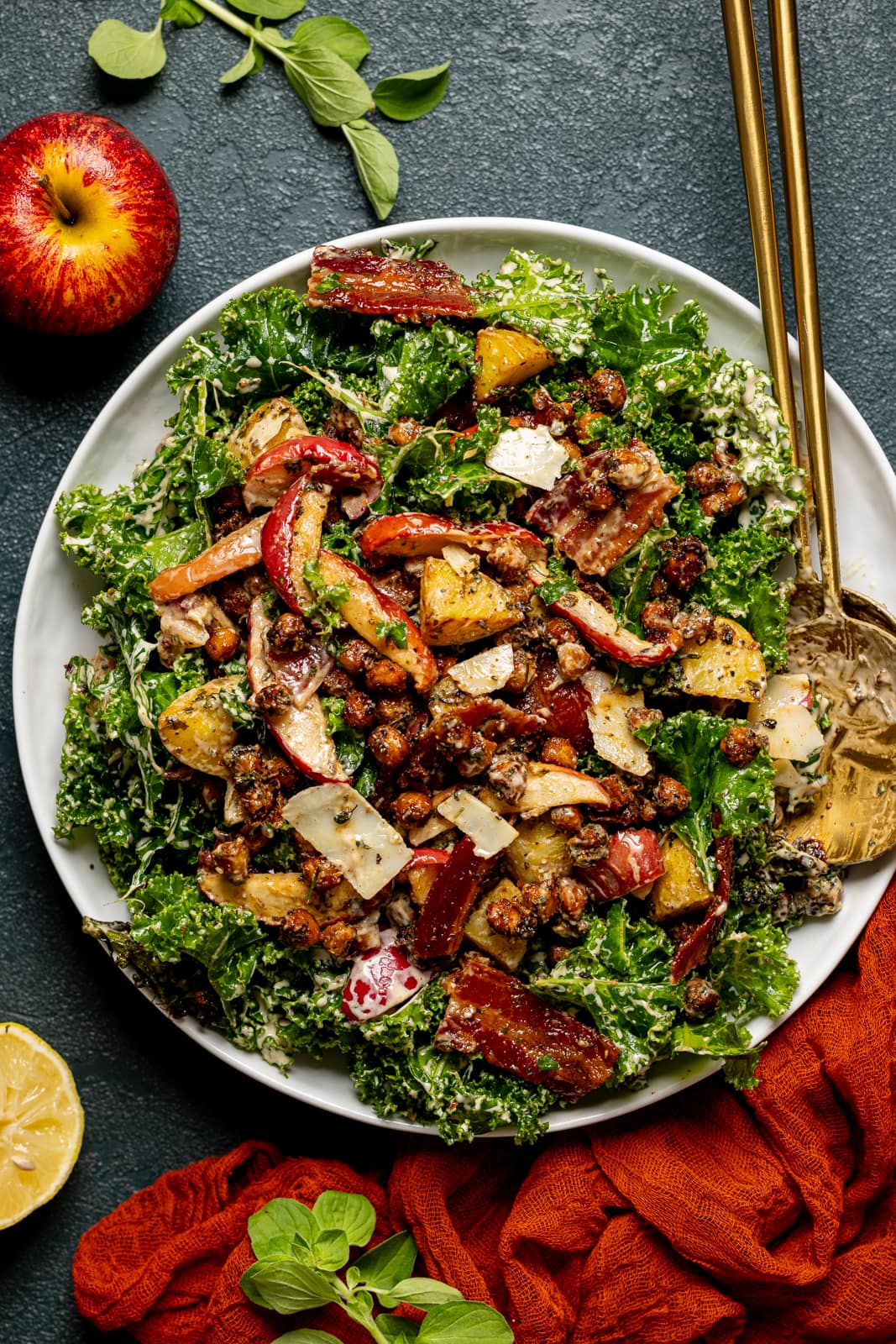 Full kale salad tossed in dressing with two gold serving spoons.