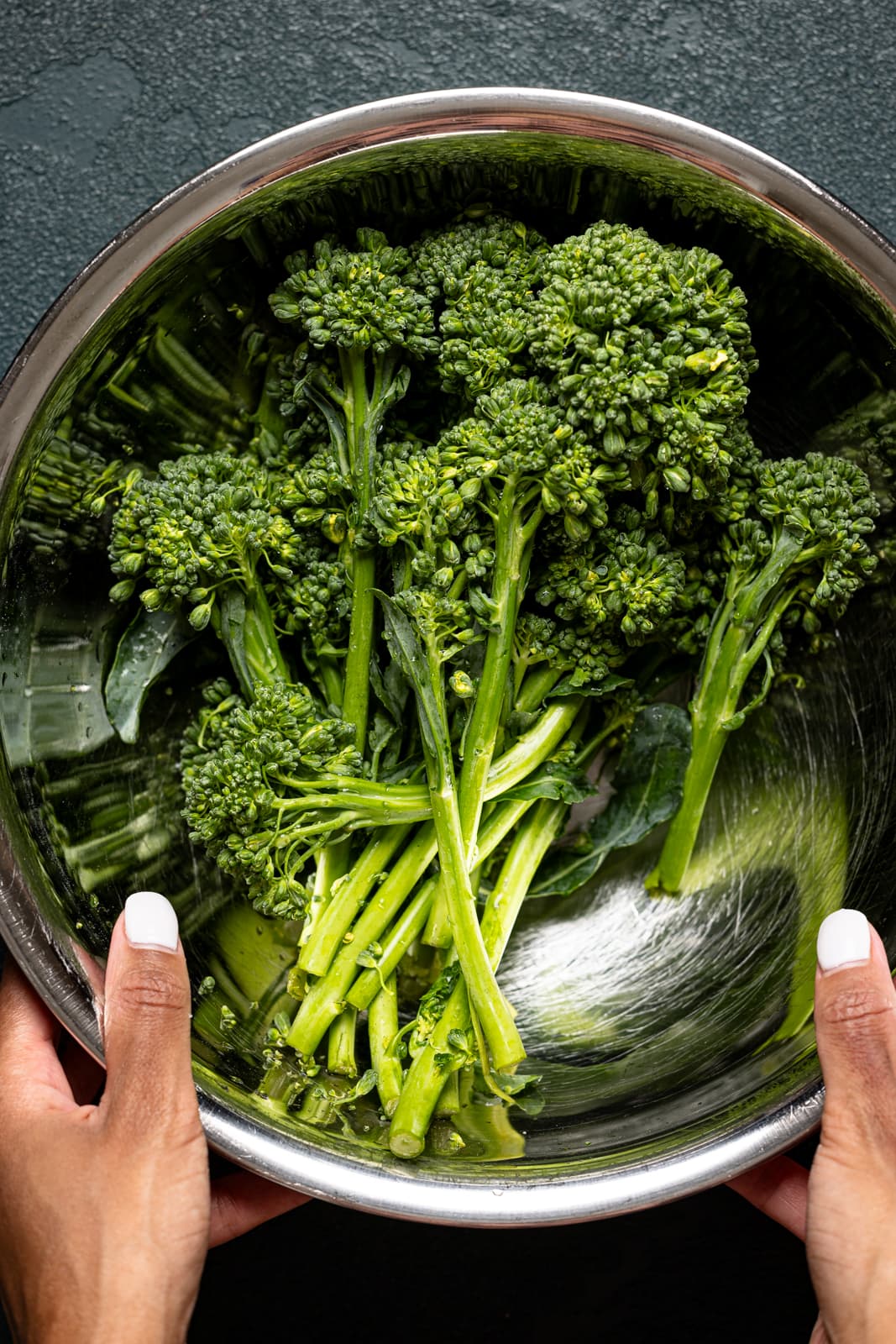 Bowl being held with broccolini. 