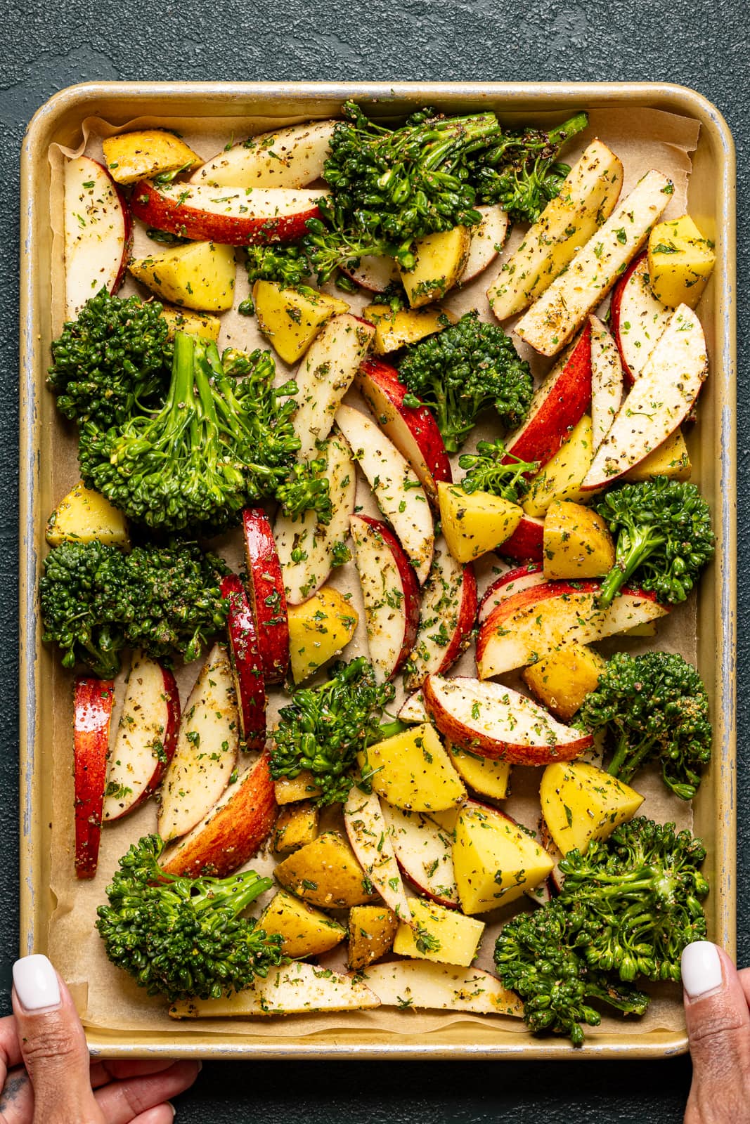 Apples and veggies lined on a baking sheet with parchment paper. 