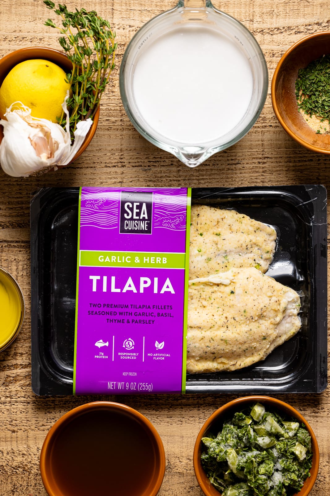 Ingredients including frozen tilapia, lemon, coconut milk, kale, herbs + seasonings, etc. 