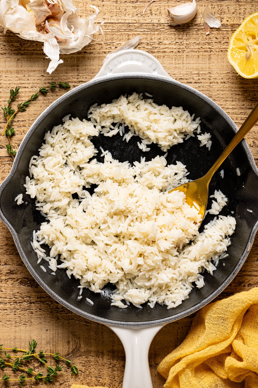 Cooked white rice in a white skillet with a gold spoon.