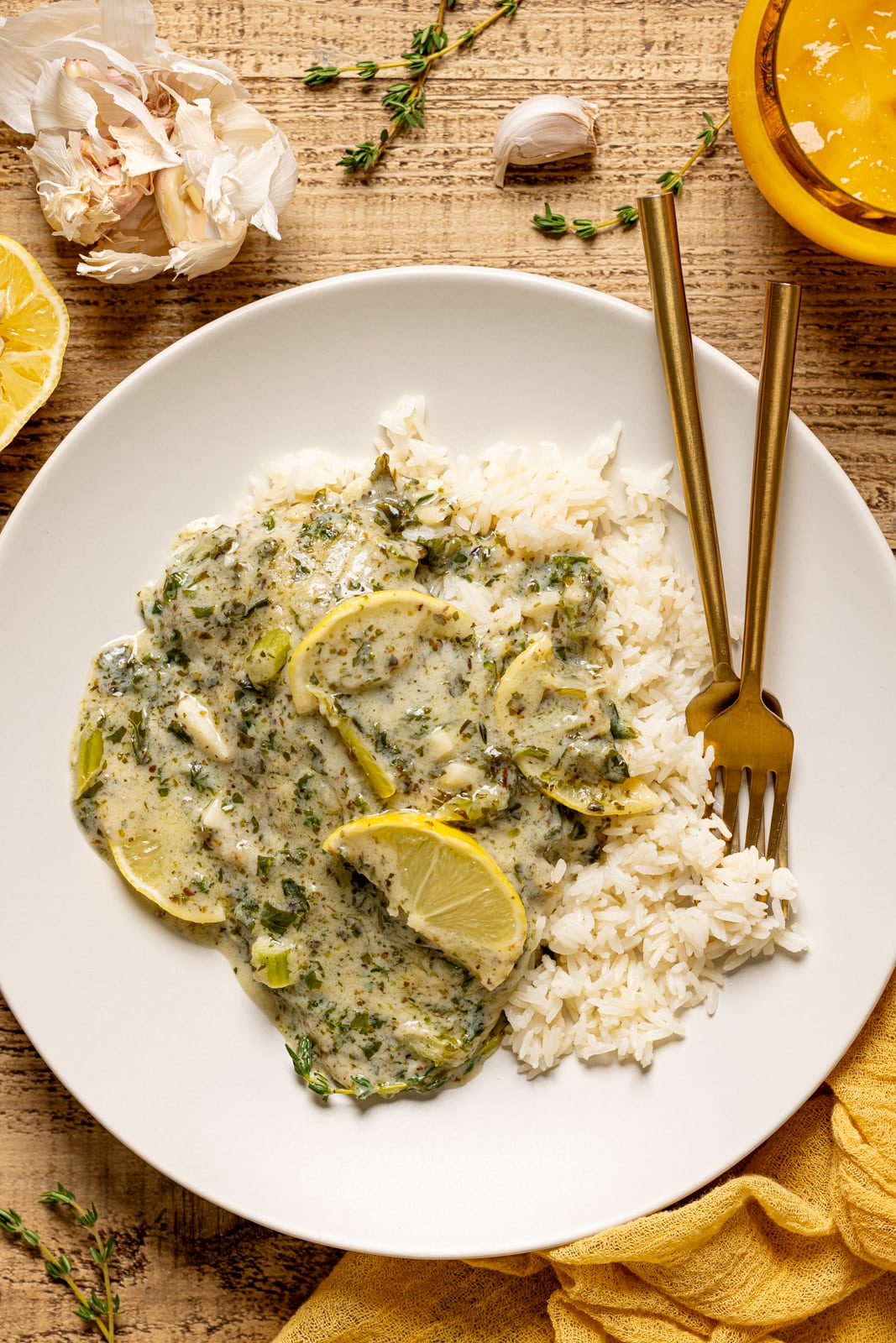 Tilapia and rice on a white plate with two forks and a glass of juice. 