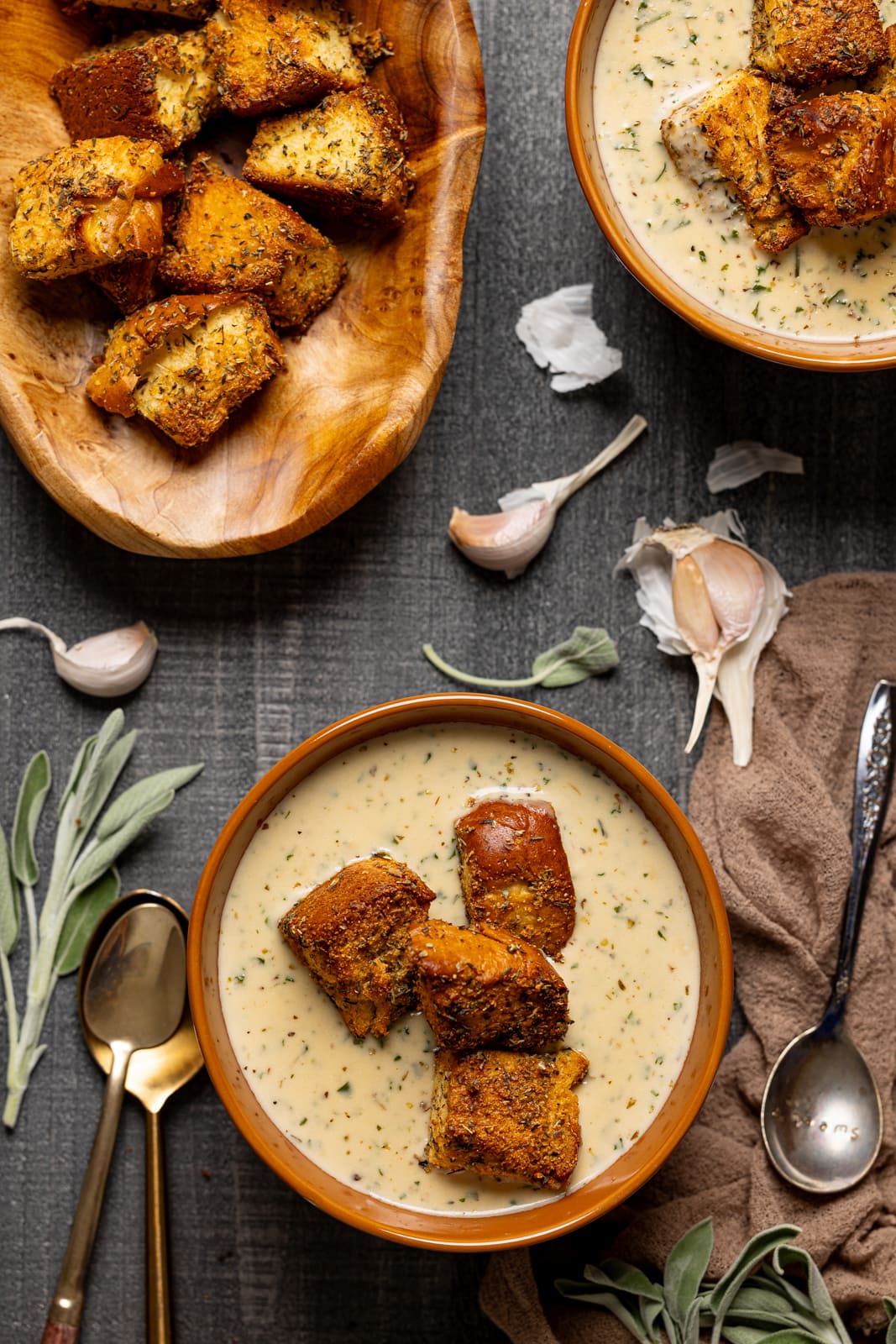 Two bowls of soup, basket of garlic bread, and spoons.