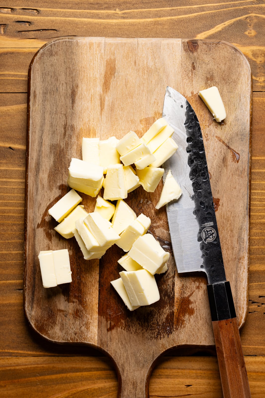 Cubed butter on a cutting board with a knife.