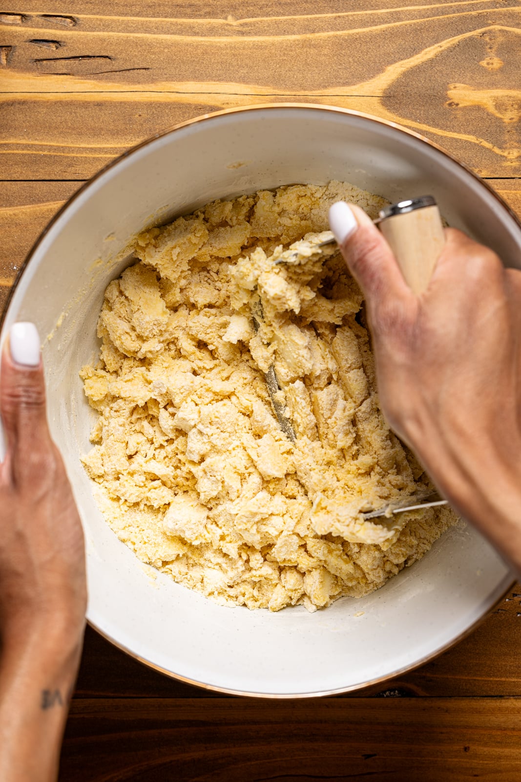 Dry ingredients together in a white bowl being mixed with hands.