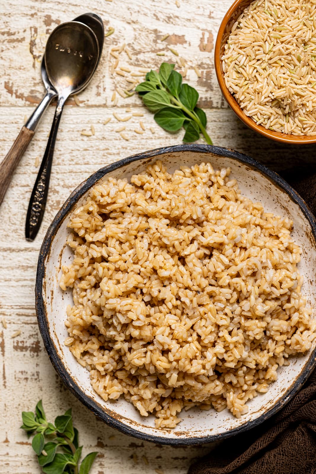 Rice in a bowl with two spoons and dry rice grains.