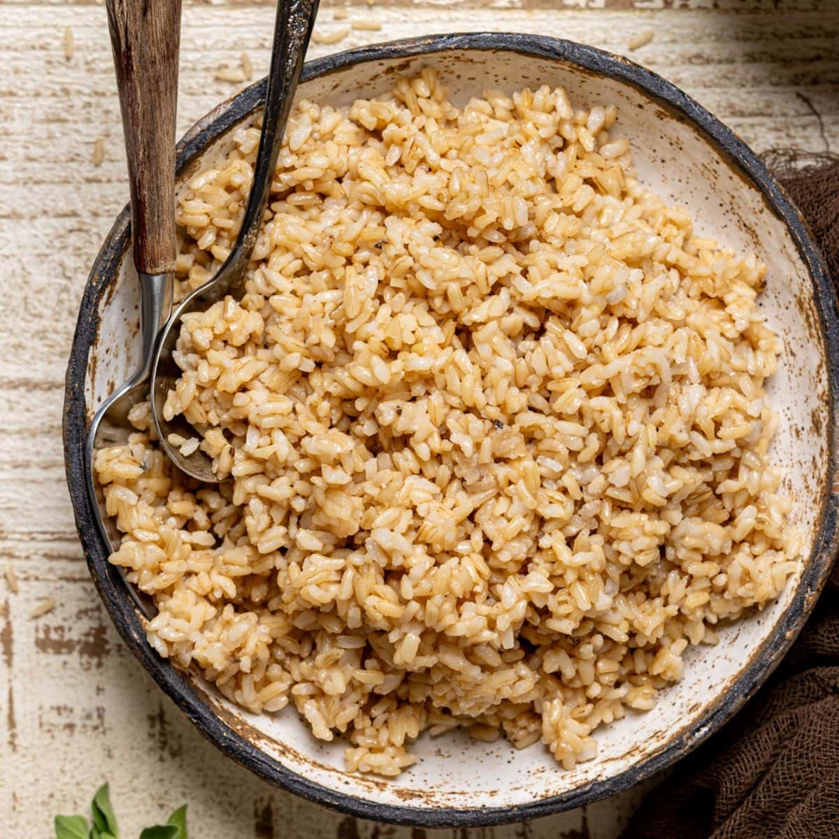 Rice in a bowl with spoons and herbs.