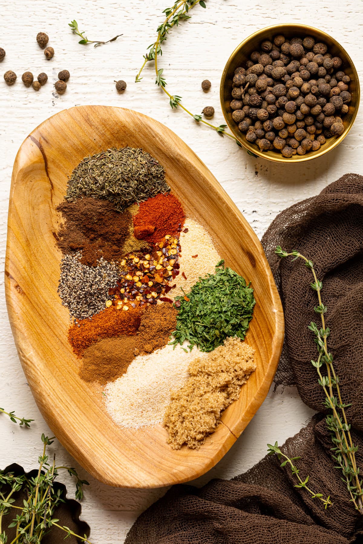 All herbs + spices in a wood bowl with pimento seeds and thyme.