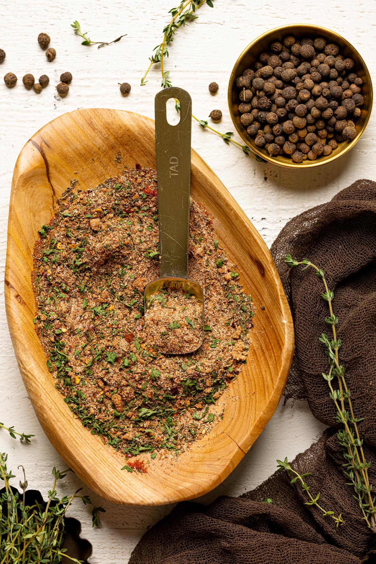 Homemade Jerk Dry Rub Seasoning in a wood bowl with pimento seeds and thyme sprigs.  