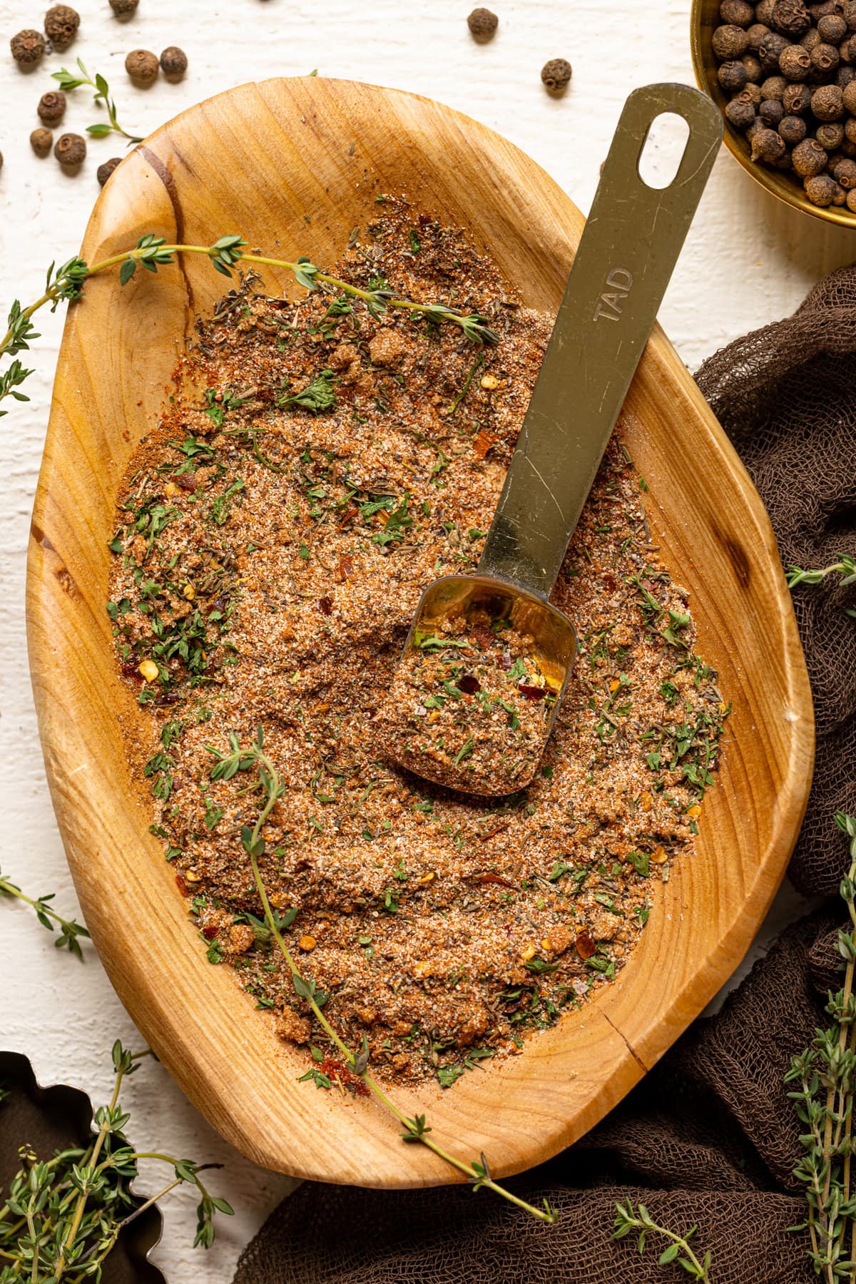 Seasoning blend in a wood bowl with thyme sprigs and gold spoon.