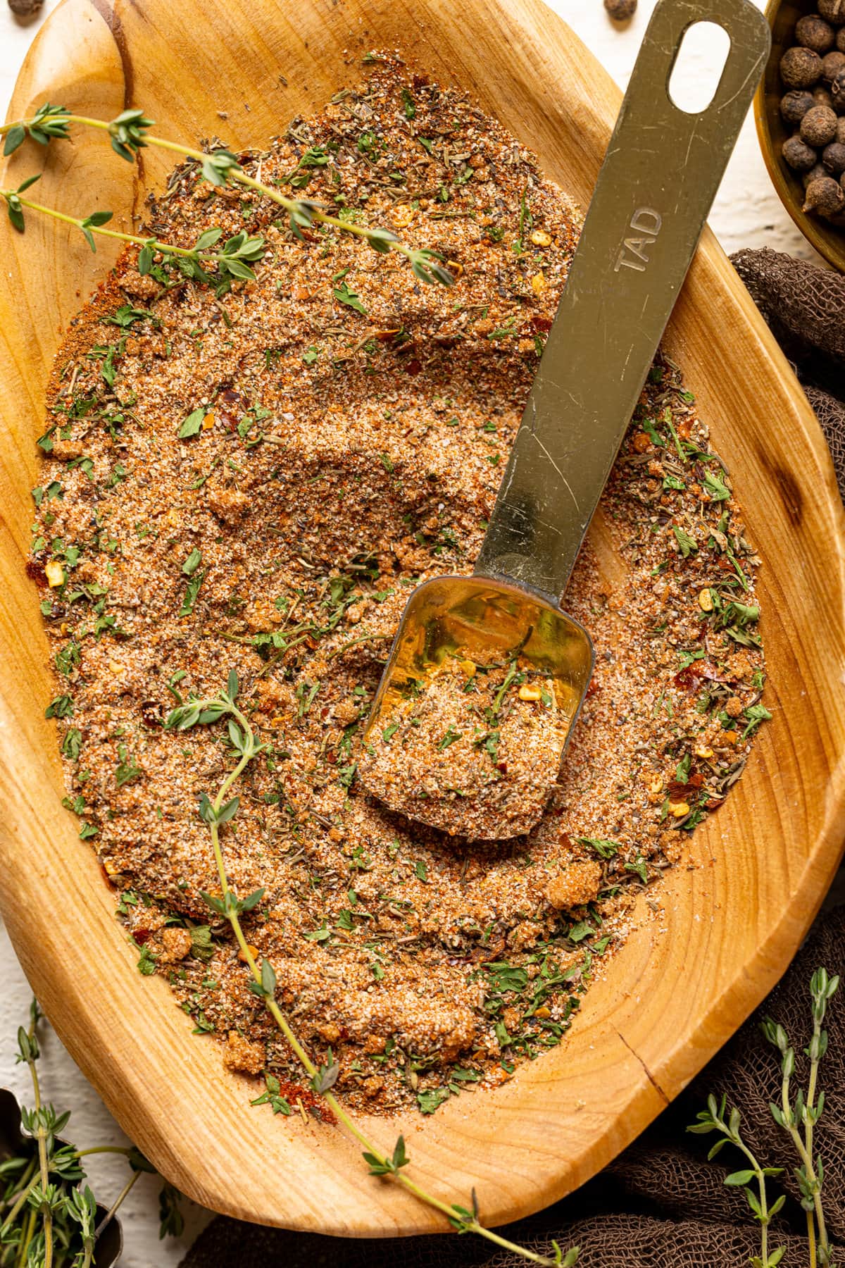 Up close shot of dry seasoning in a wood bowl with a spoon.