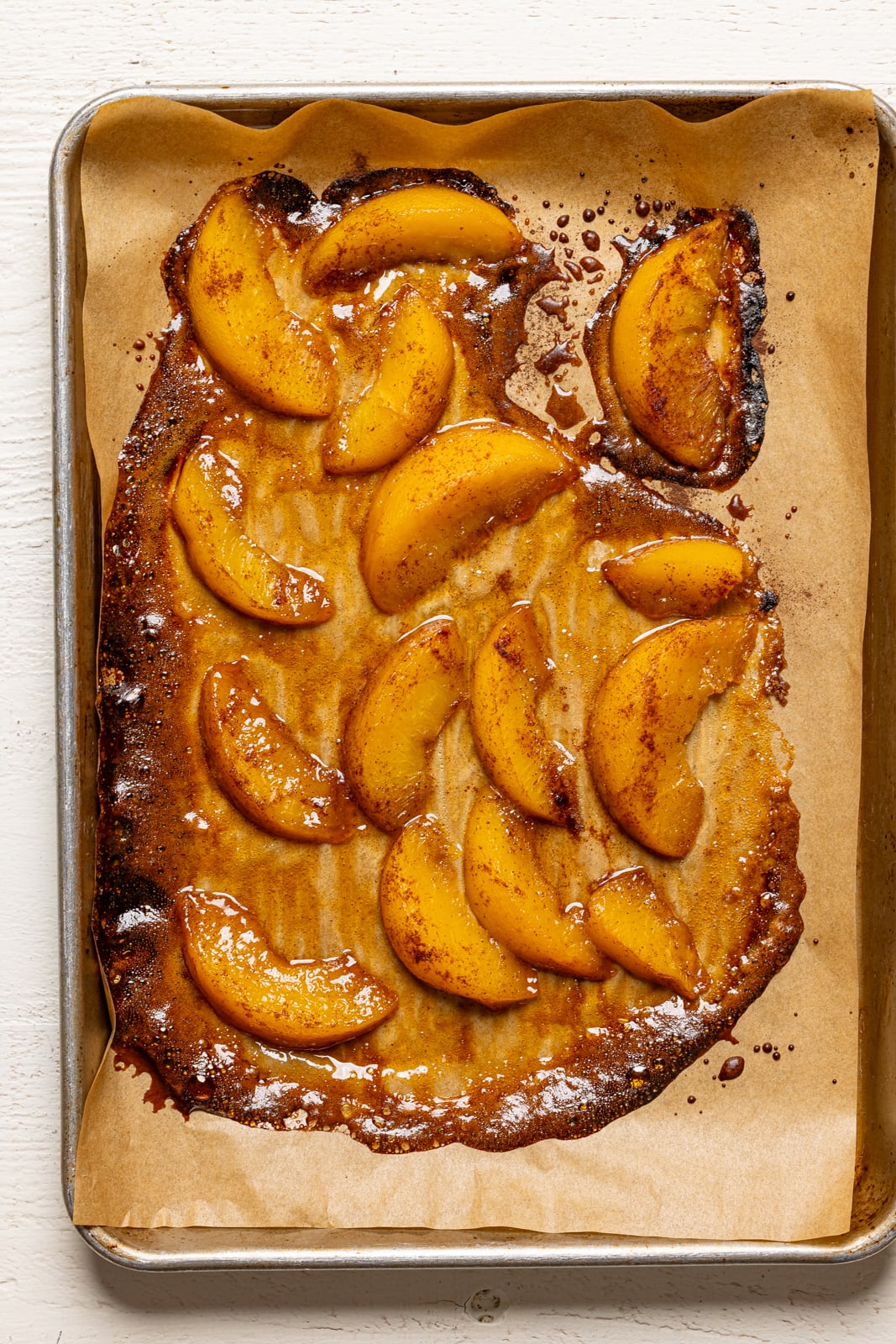 Roasted peaches on a baking sheet with parchment paper.