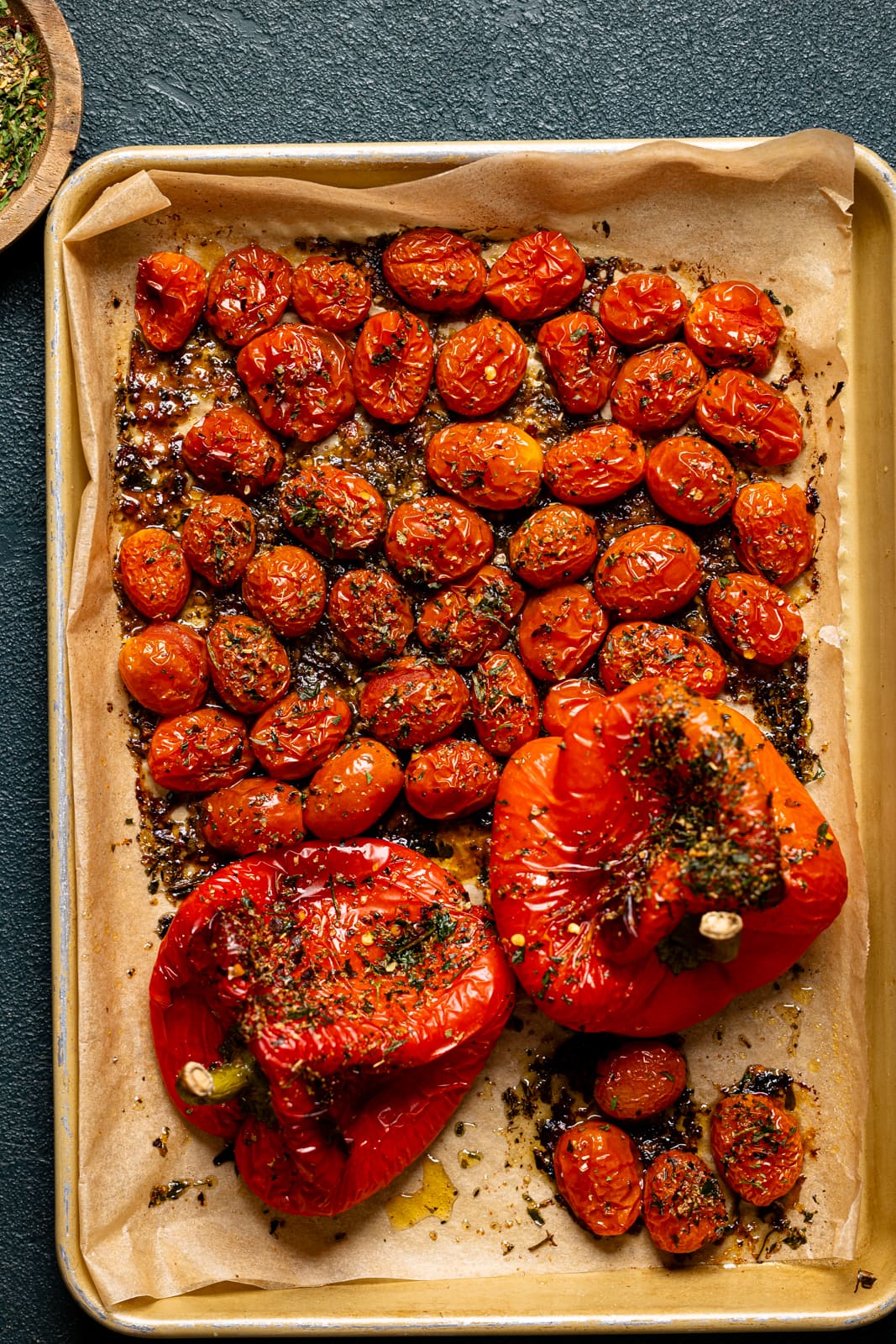 Roasted red peppers and tomatoes on a baking sheet with parchment paper.