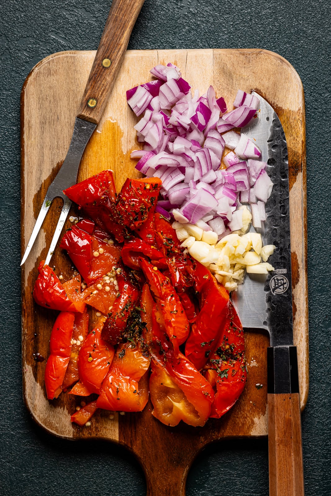 Chopped veggies on a cutting board with a fork and knife.