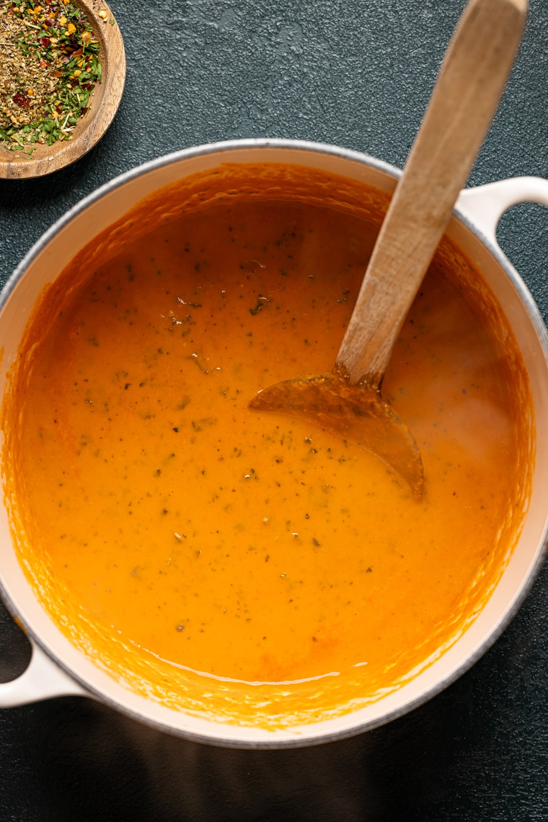 Soup in a white pot with a wooden spoon.