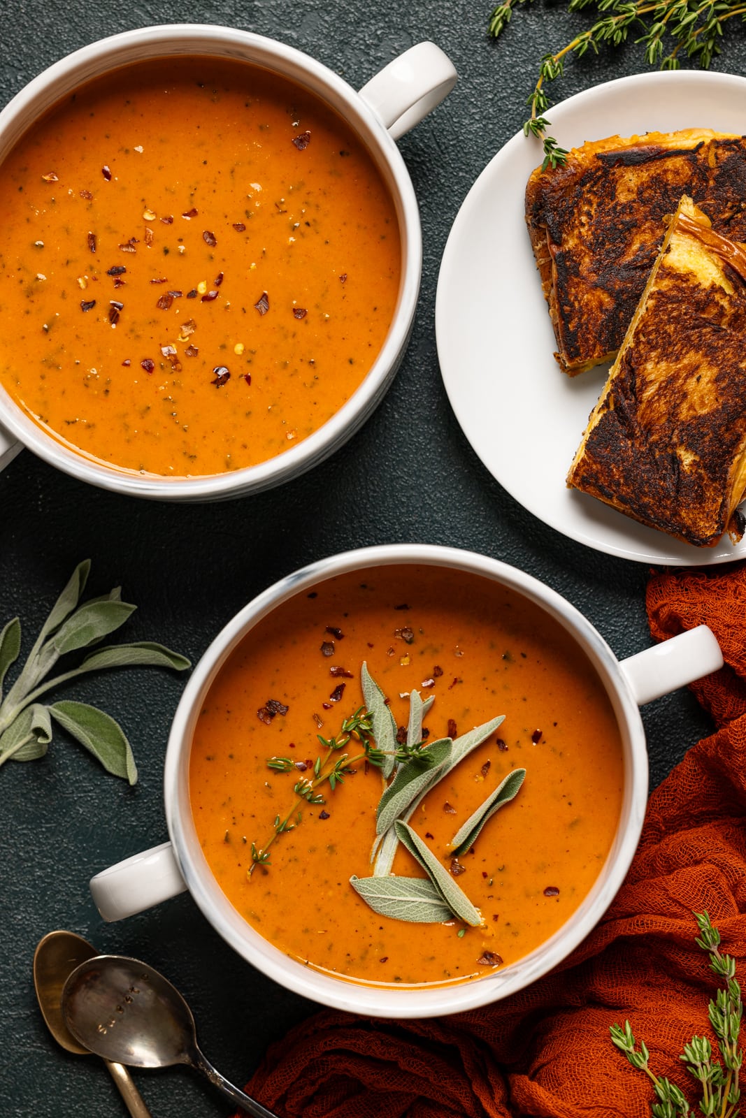 Soup in two white bowls and a side of grilled cheese.