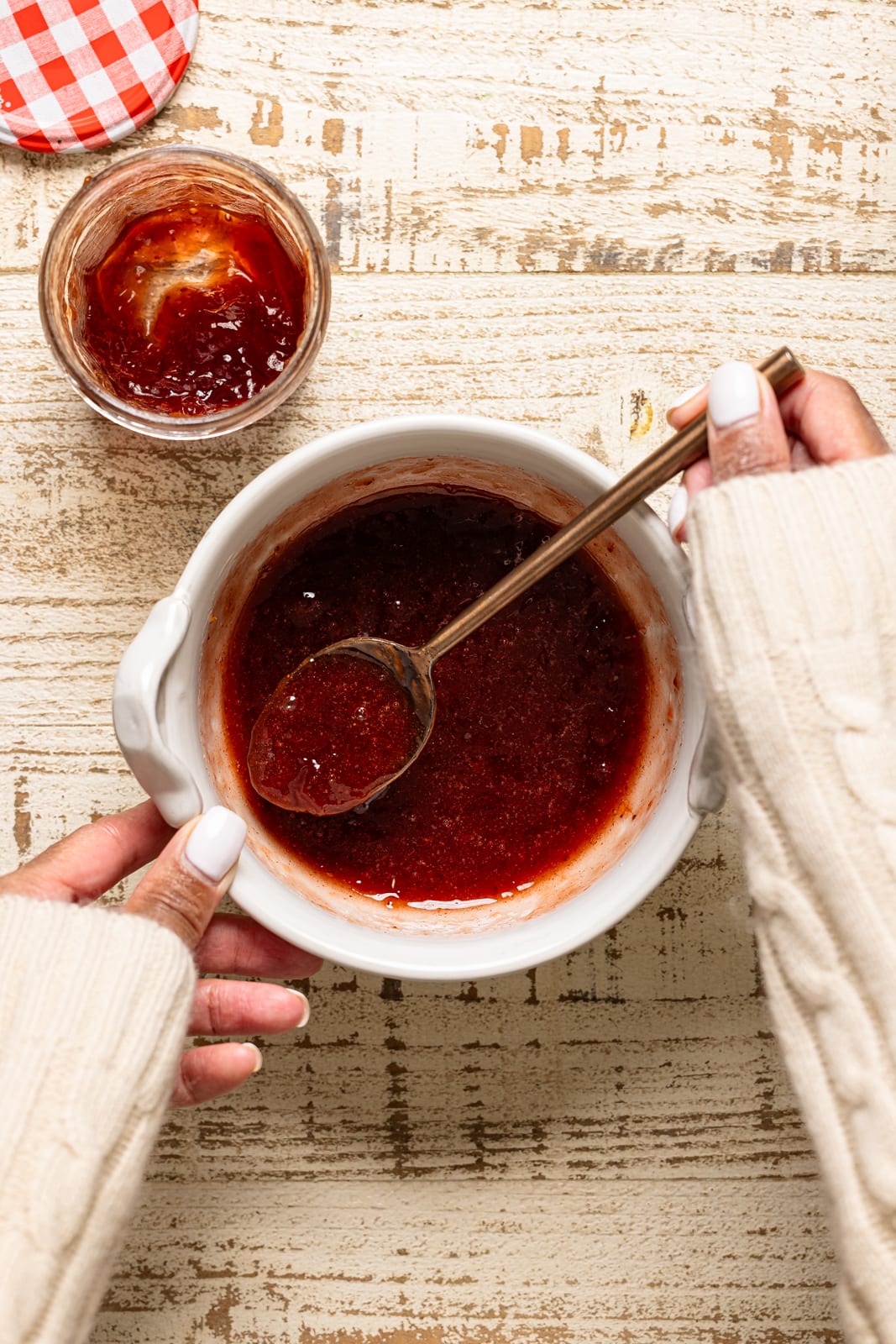 A bowl of jam being stirred with a gold spoon.