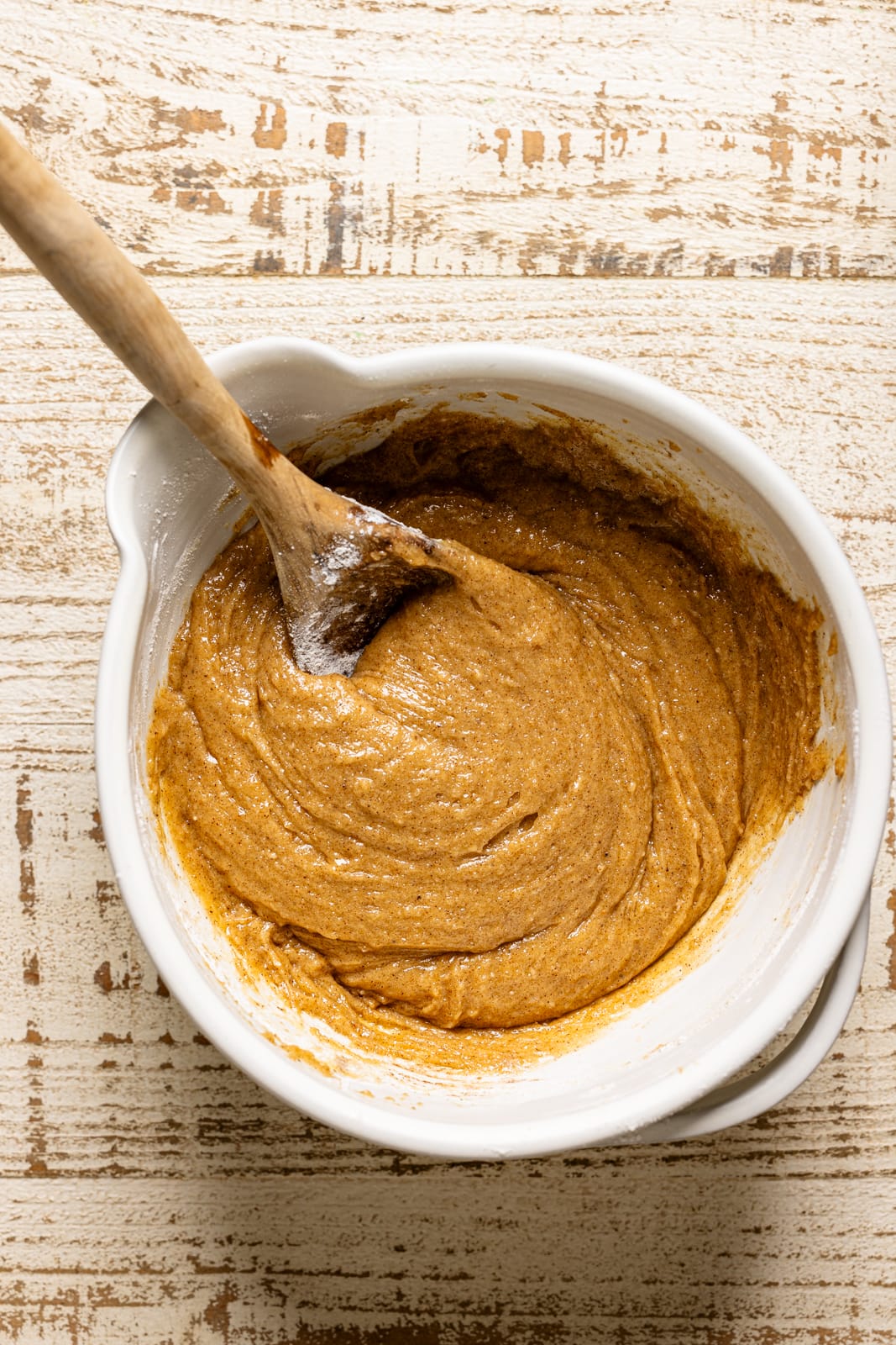 A bowl with the cake batter and a wooden spoon.