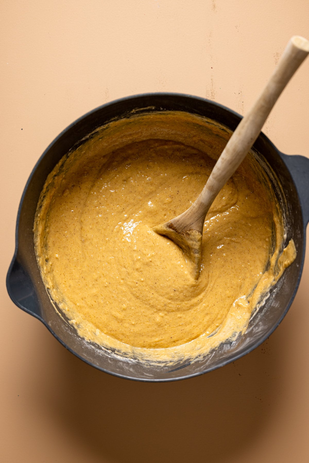 Cake batter in a large bowl with wooden spoon.