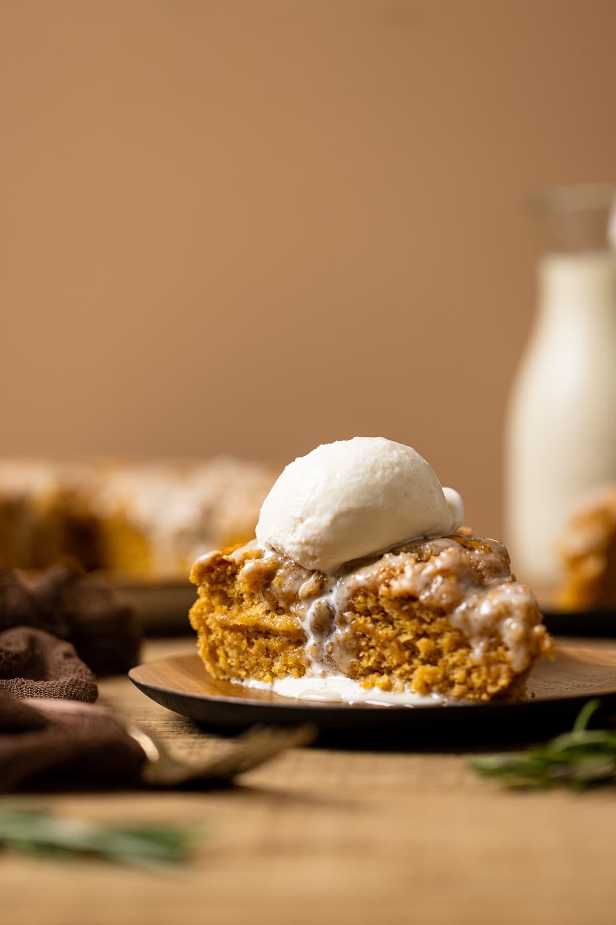 Sliced sweet potato cake on a wood plate with a fork and scoop of ice cream on top.