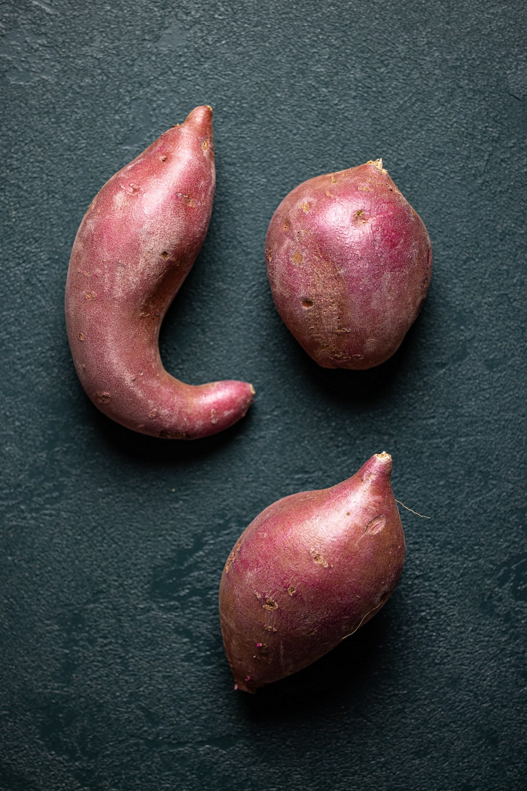 Sweet potatoes on a dark green table.