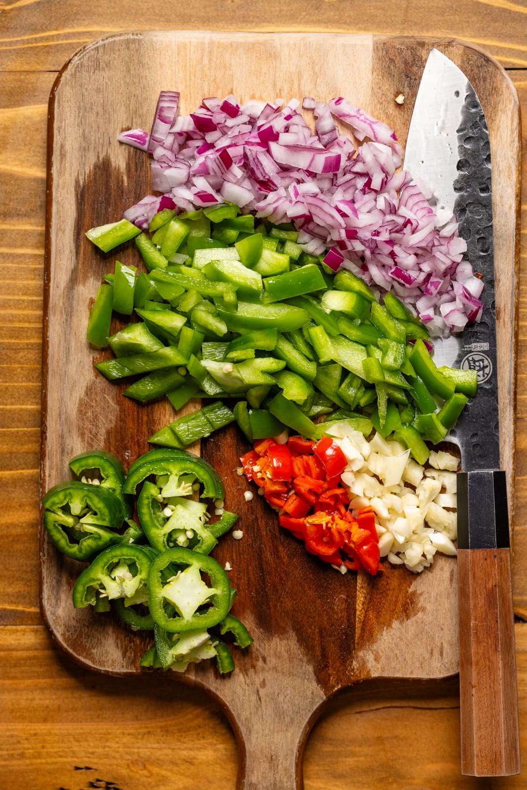 Veggies chopped on a cutting board with a knife. 