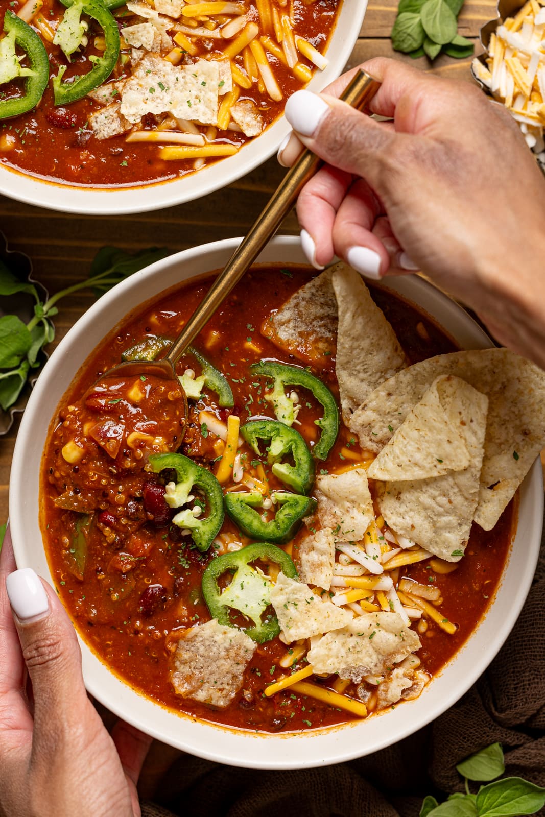 Bowl of soup being held with hands and a spoon.