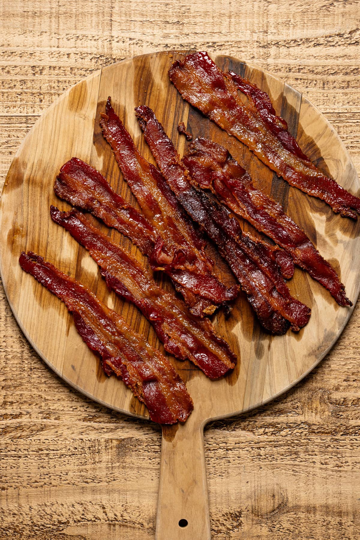Candied bacon on a wooden cutting board.