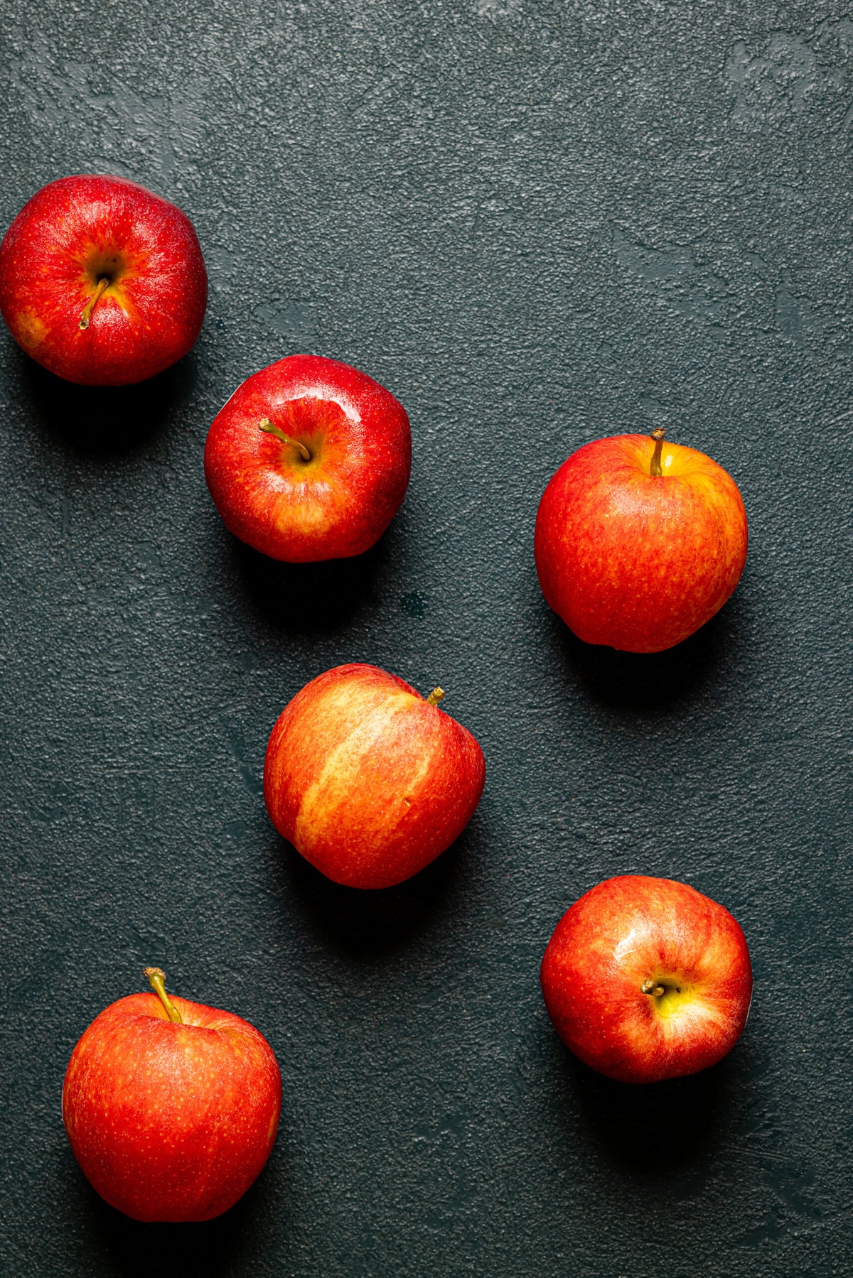 Group of red apples on a dark green table.