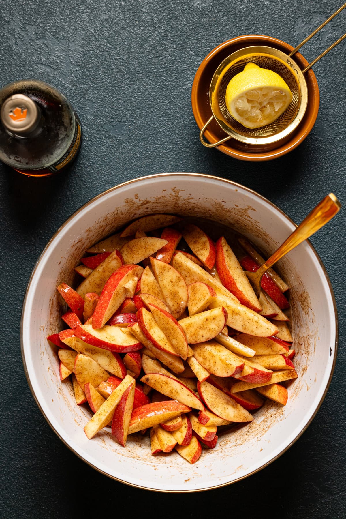 Sliced apple filling in a white bowl with a spoon and a lemon on the side.