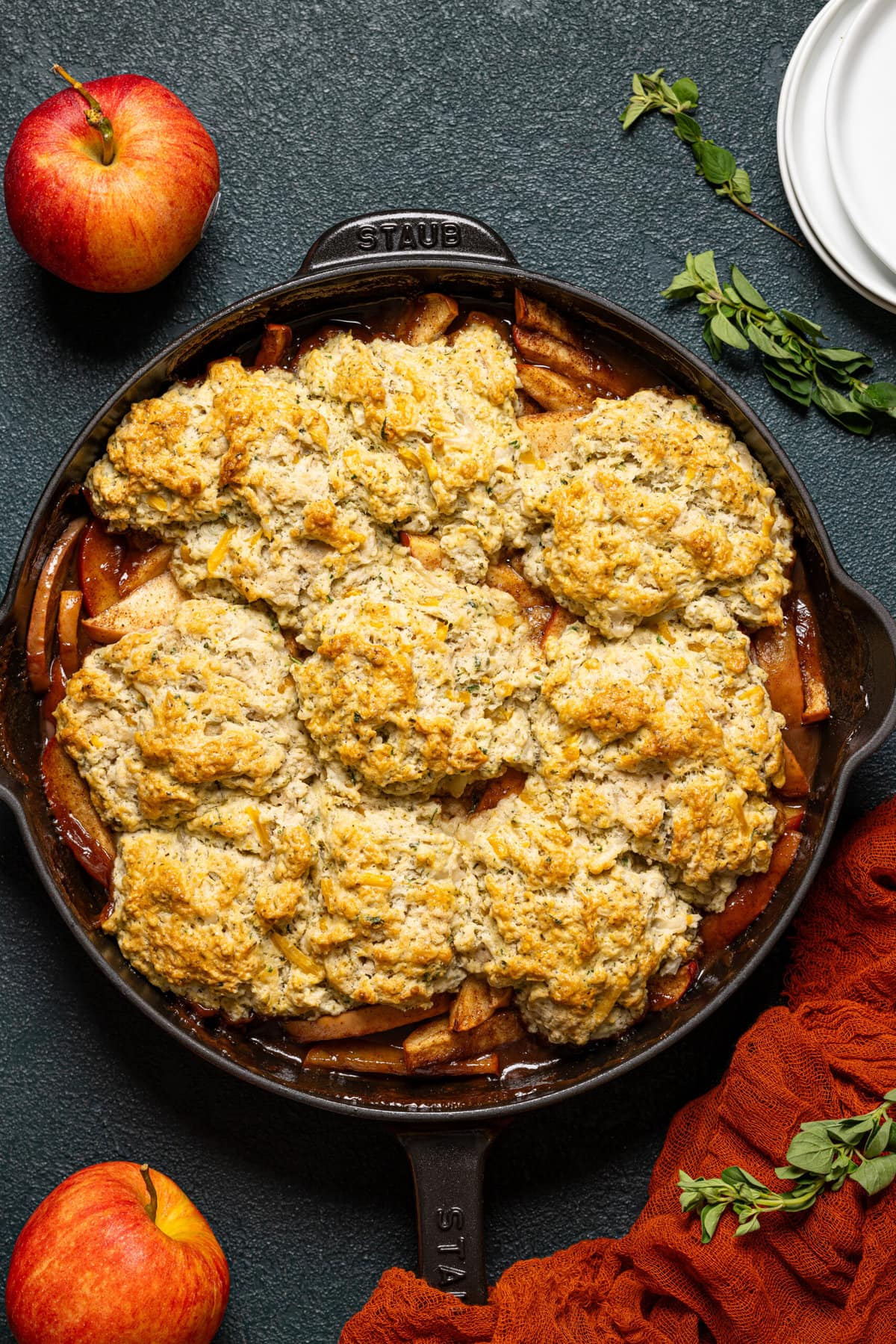 Baked cobbler in a skillet with two apples.
