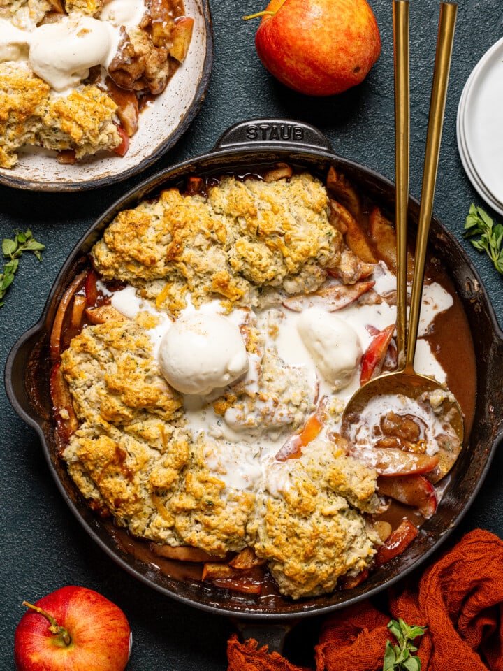 Baked cobbler scooped out with two serving spoons and apples.