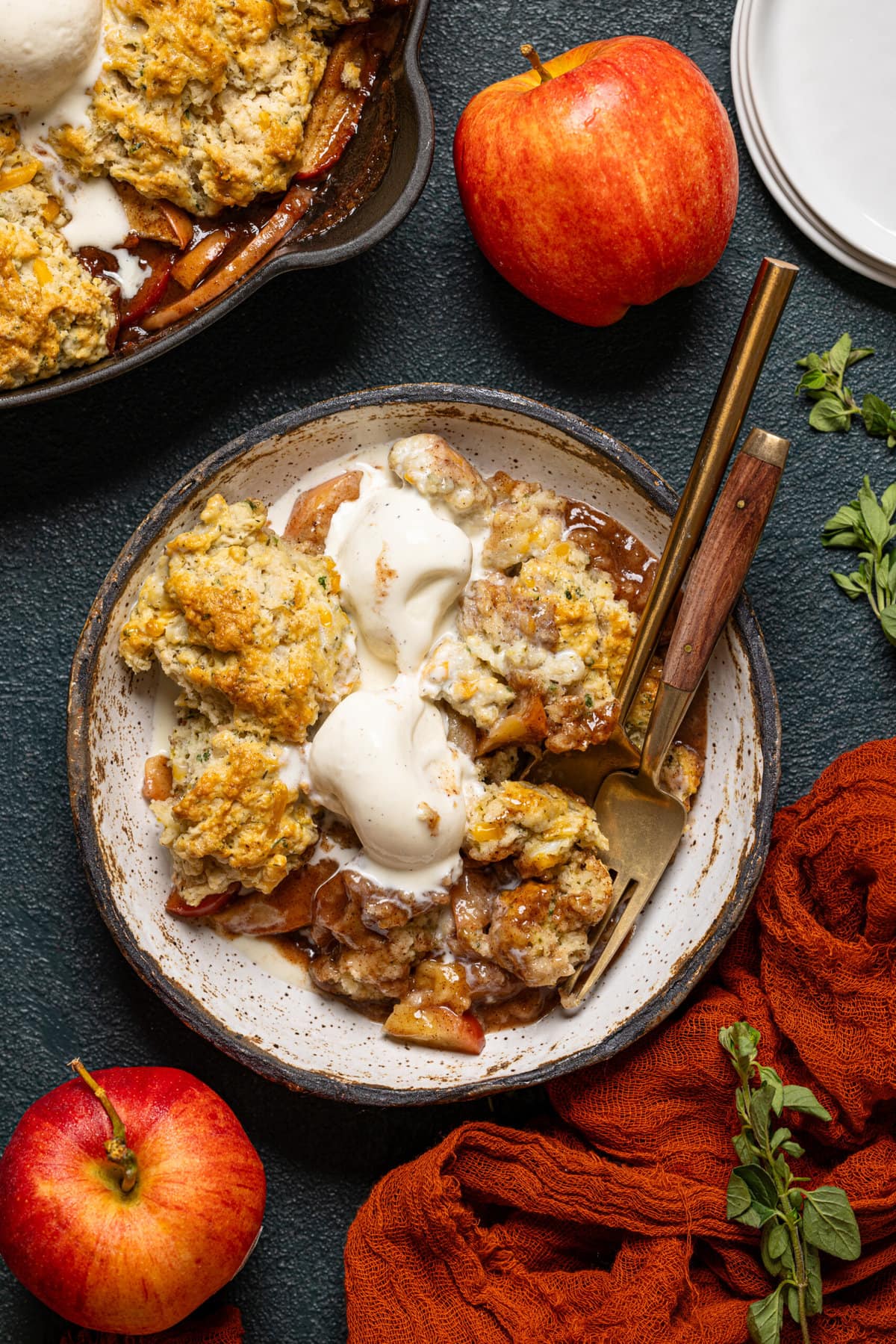 Cobbler in a bowl with two forks and scoops of ice cream on top.