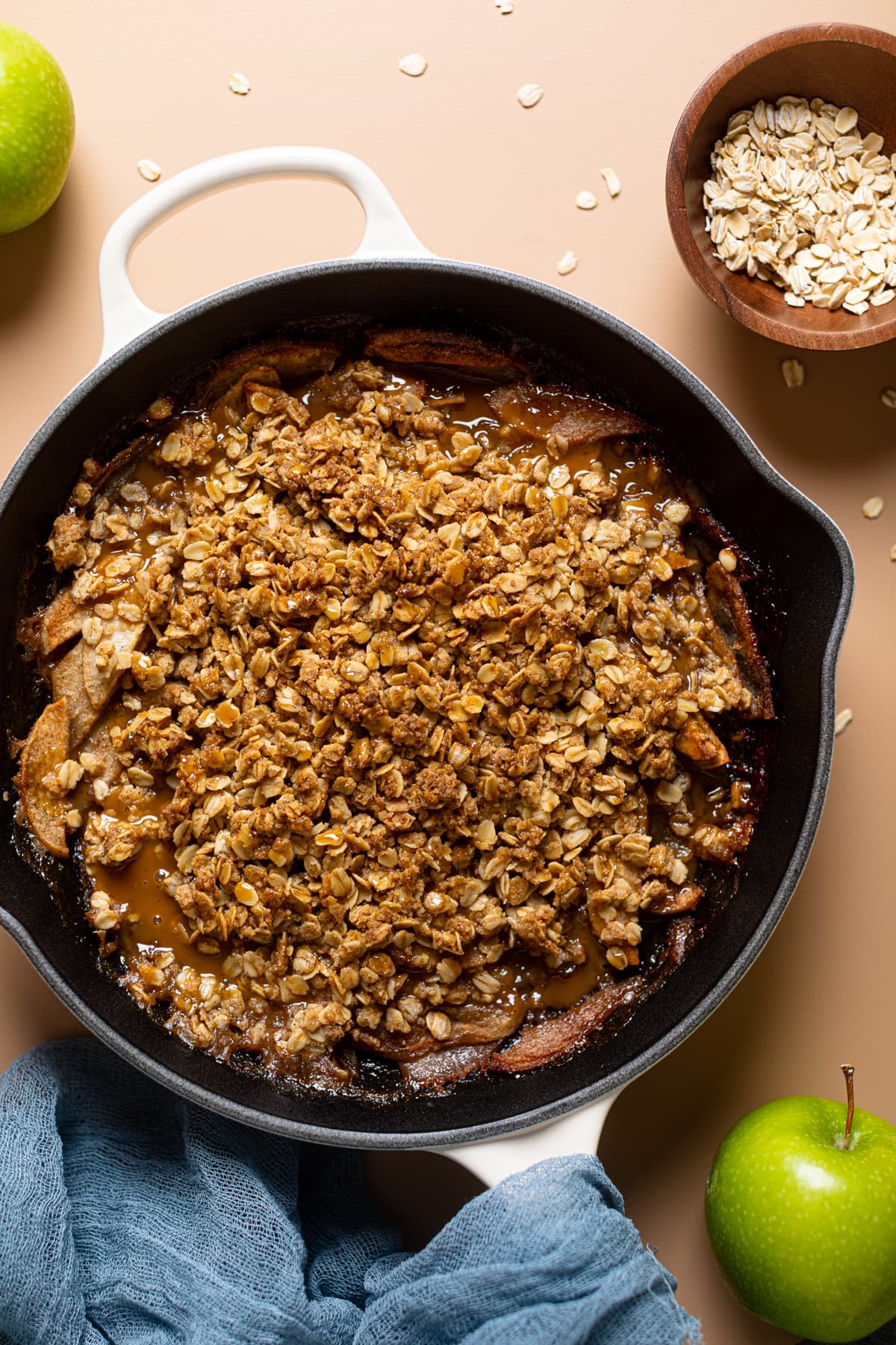 Apple pear crisp in a white skillet with apples and oats. 