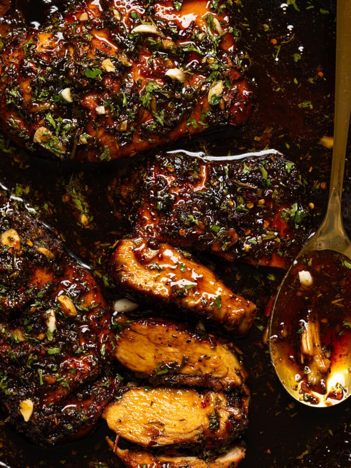 Up close shot of chicken breasts in a skillet with spoon.