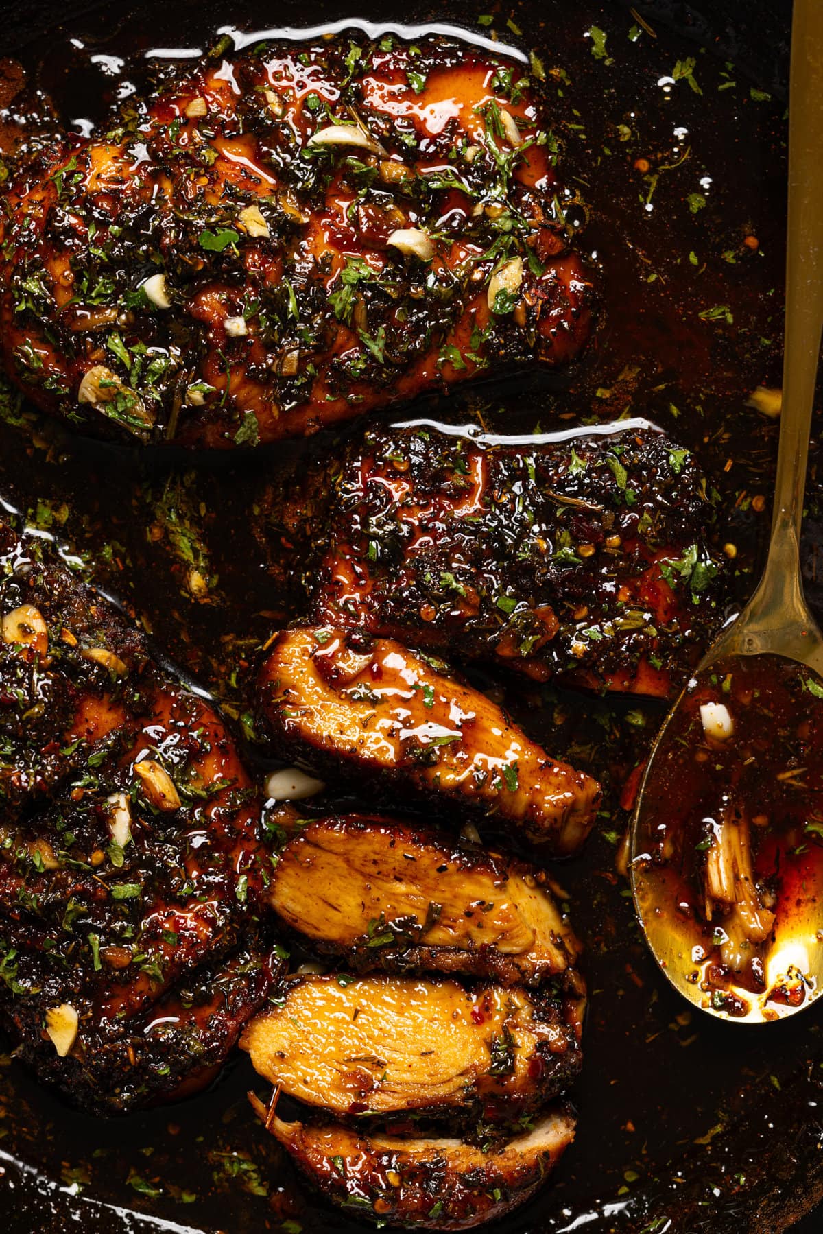 Up close shot of chicken breasts in a skillet with spoon.
